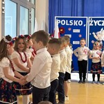Dziewczynki stoją naprzeciwko chłopców, trzymając się za ręce.